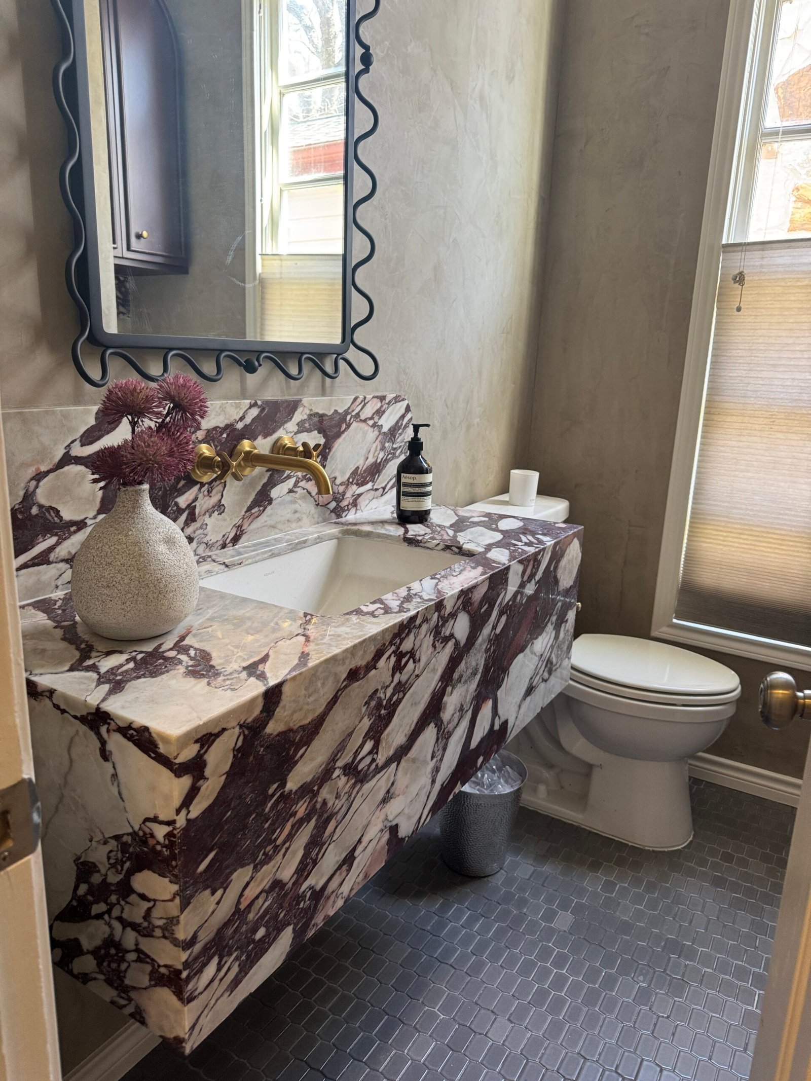 Waterfall vanity in heavily veined marble with brass fittings