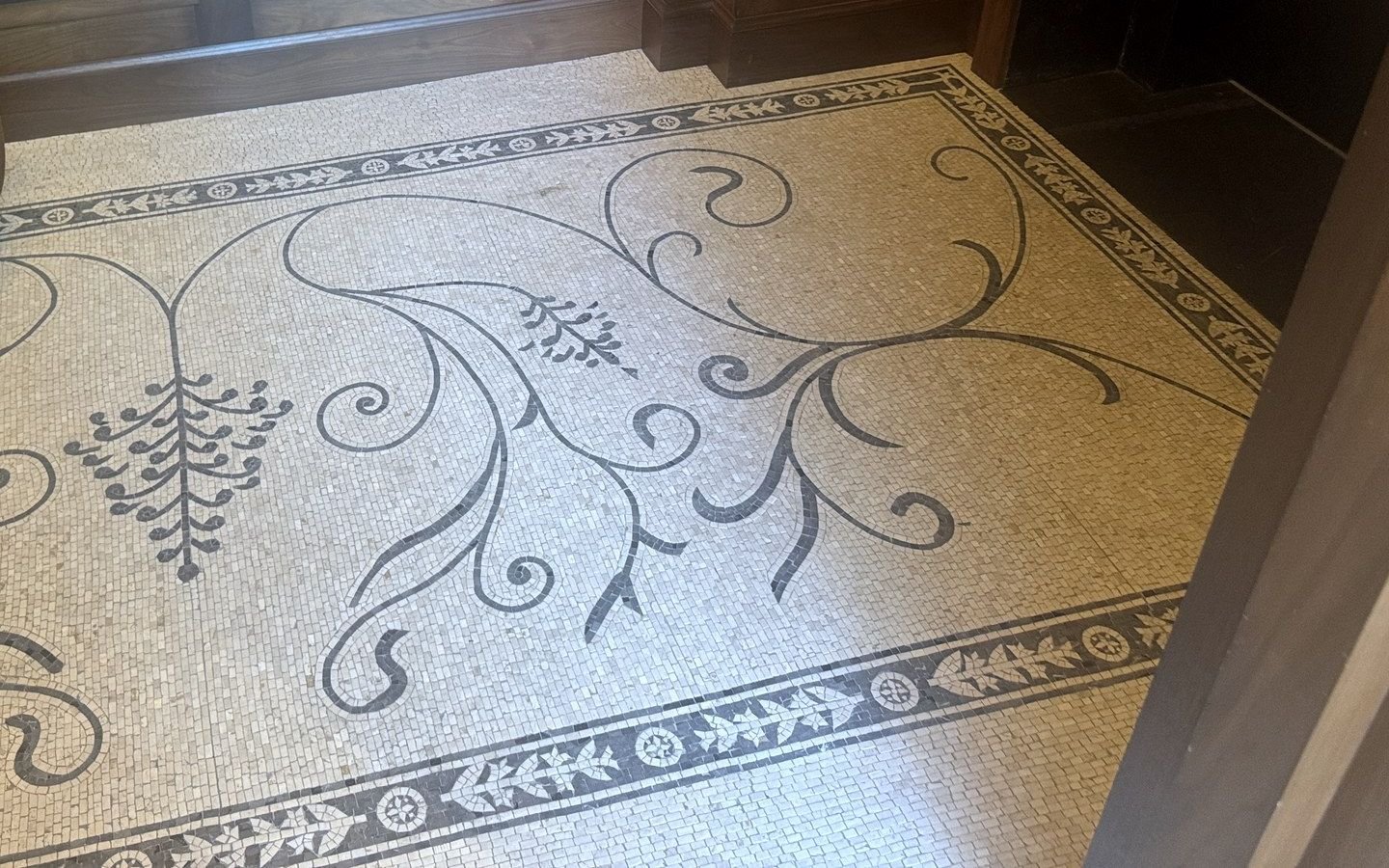 Decorative mosaic floor with a scrolling central pattern and border