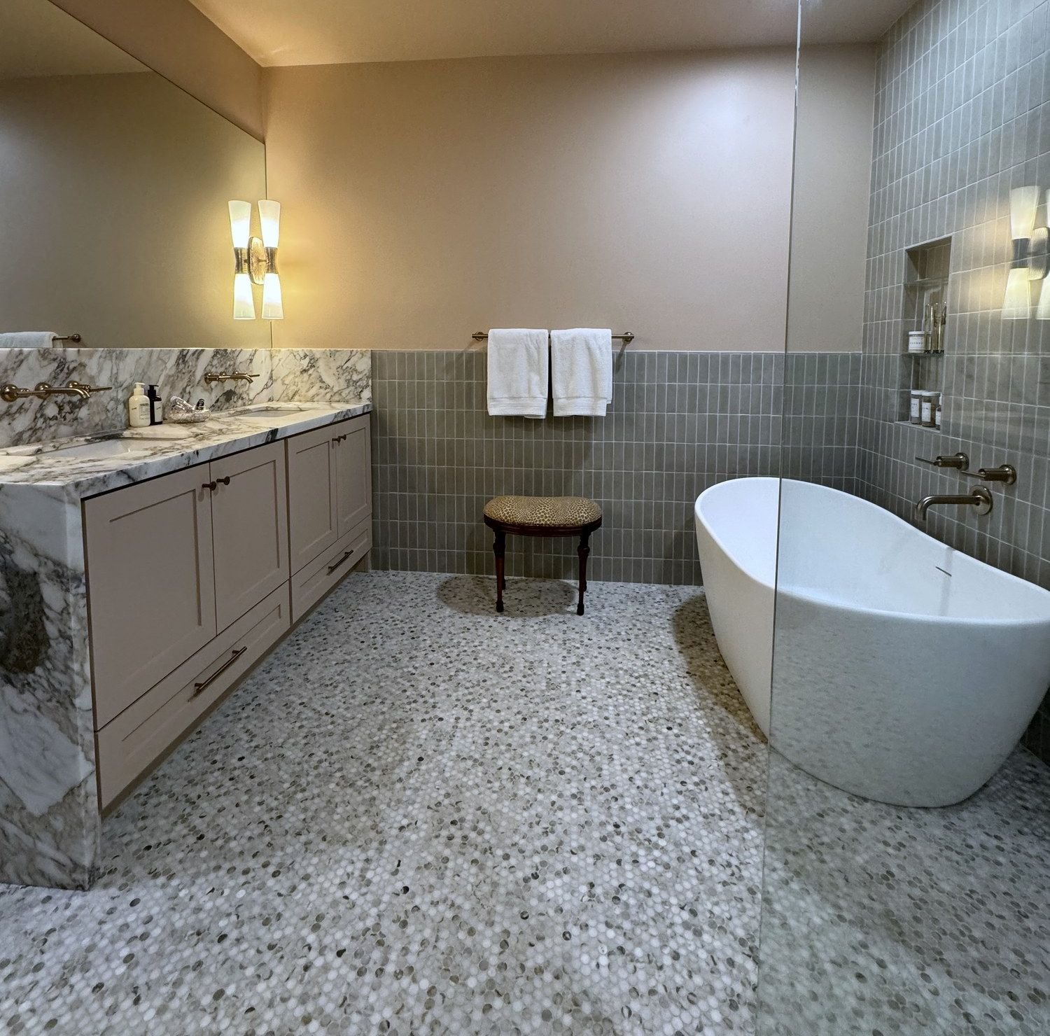 Bathroom with a freestanding bath, tiled walls and pebble floor