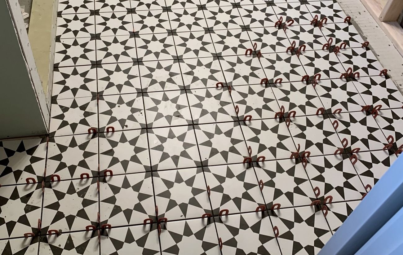 Patterned floor tile being aligned with leveling clips during installation