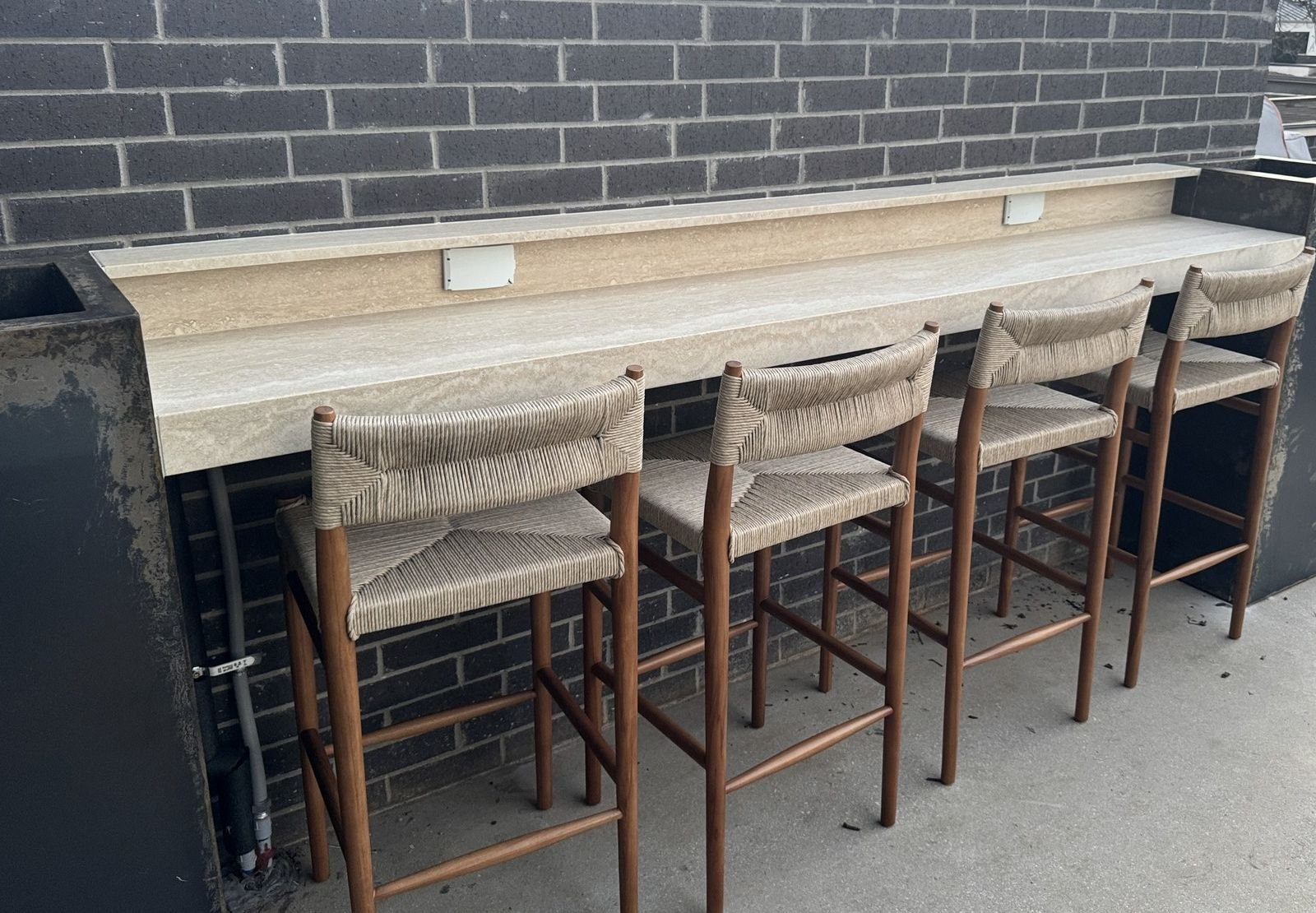 Bar stools at a stone counter beneath a dark tiled wall